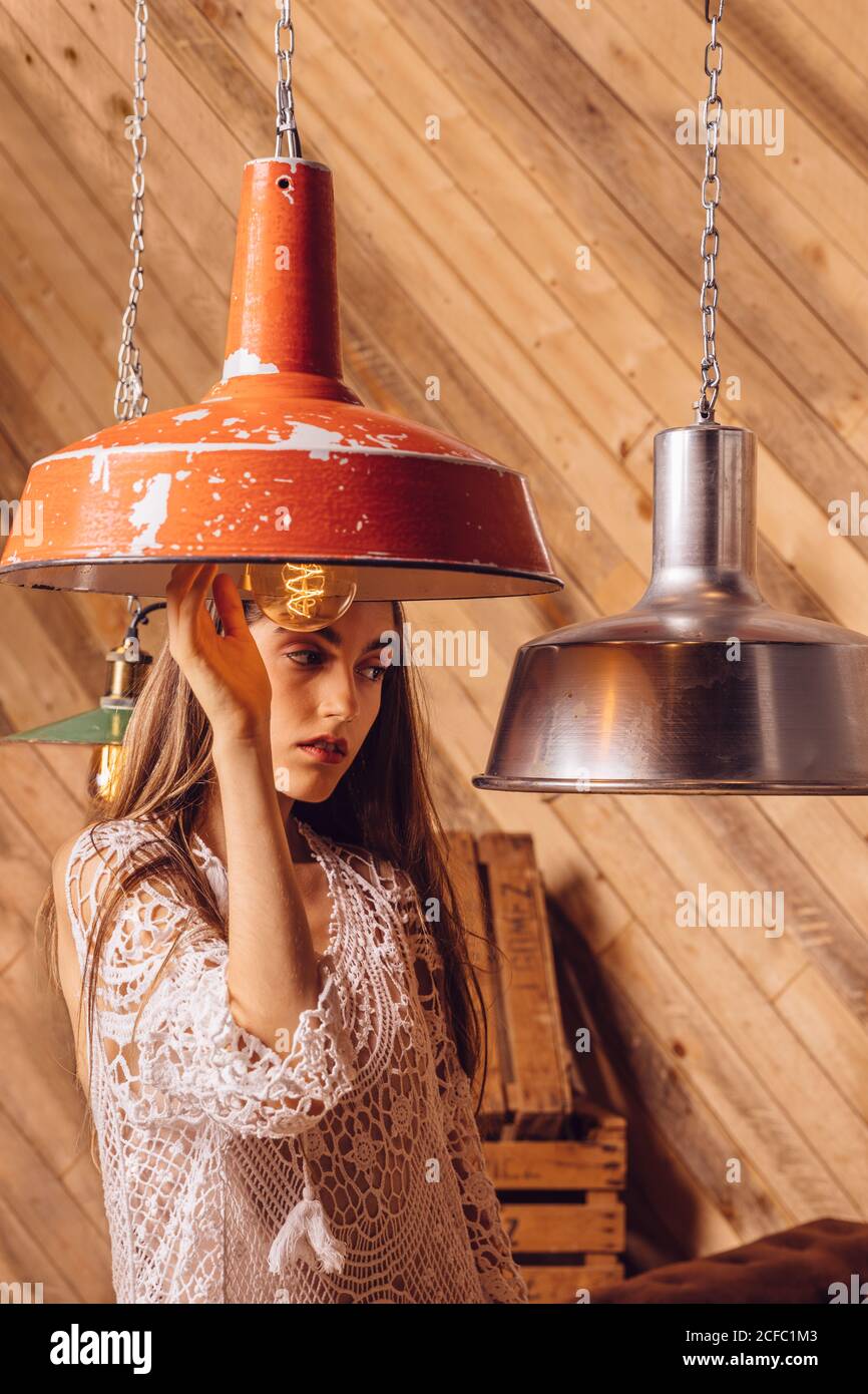 Young Woman posing between ceiling lamps on wooden background Stock Photo