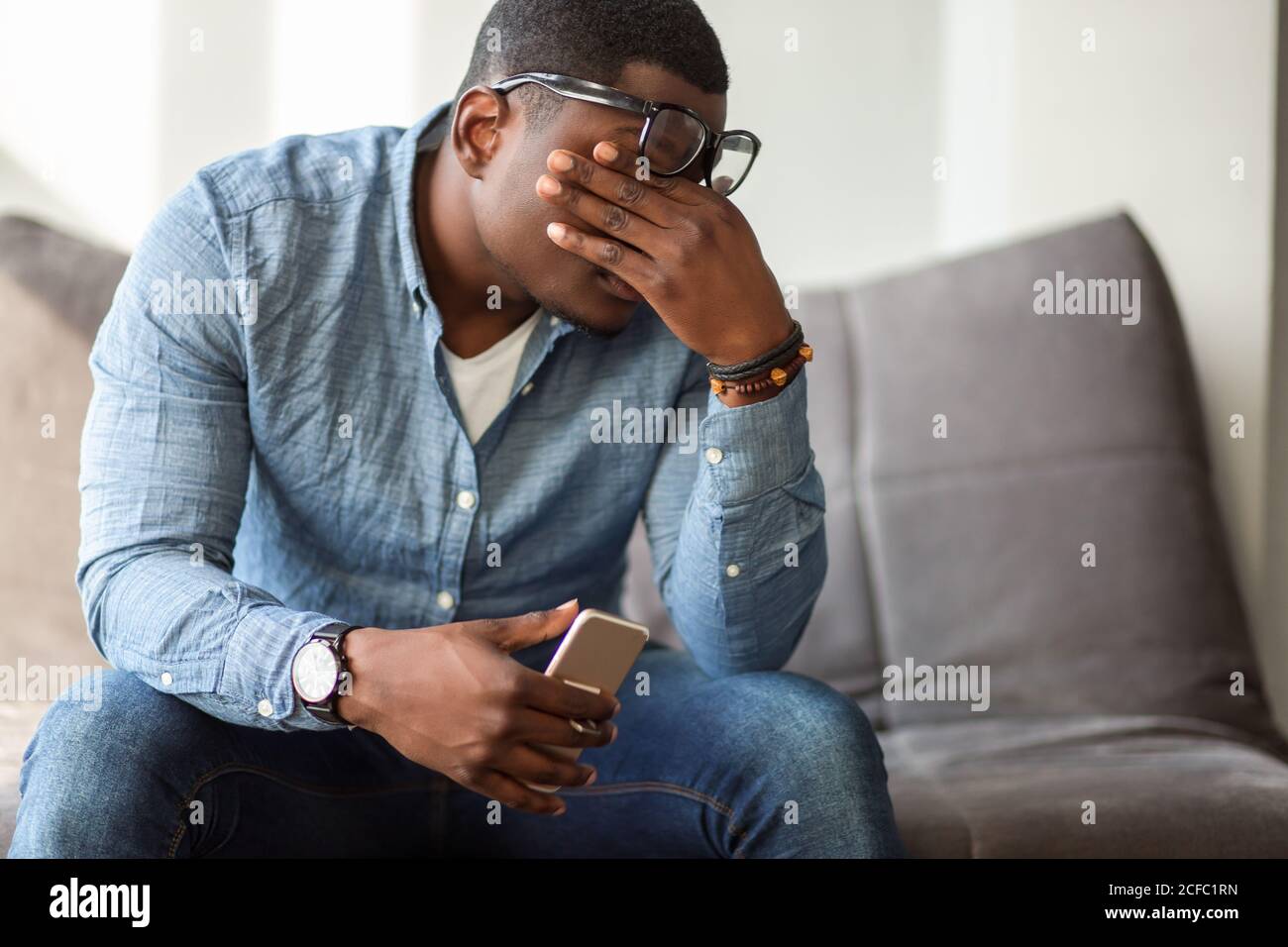 Feeling exhausted. Frustrated young black man massaging his nose ...