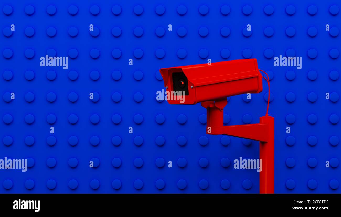 Red surveillance camera on blue background monitoring people on the street. Camera to search for quarantine offenders caused by Coronavirus Stock Photo