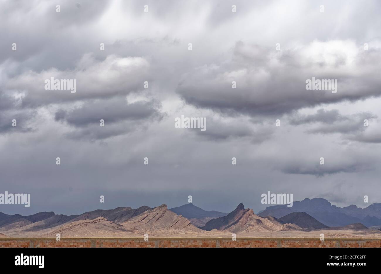 brick wall, dark clouds, Sahara Desert near Erfoud, morocco,fes, North Africa, arid landscape, cloud cover Stock Photo