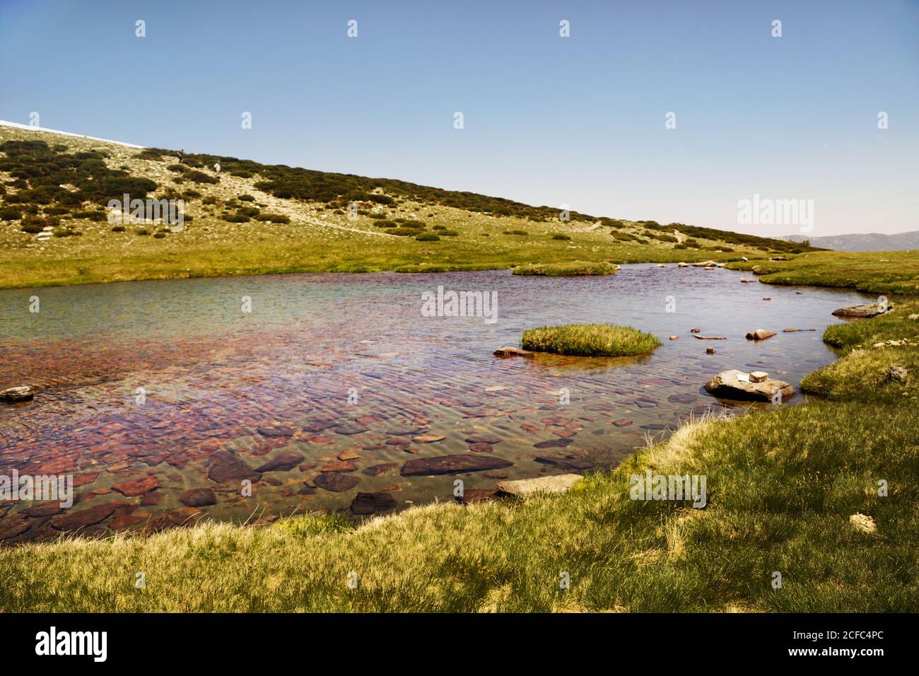 Clear lake at bottom of rocky mountain Stock Photo