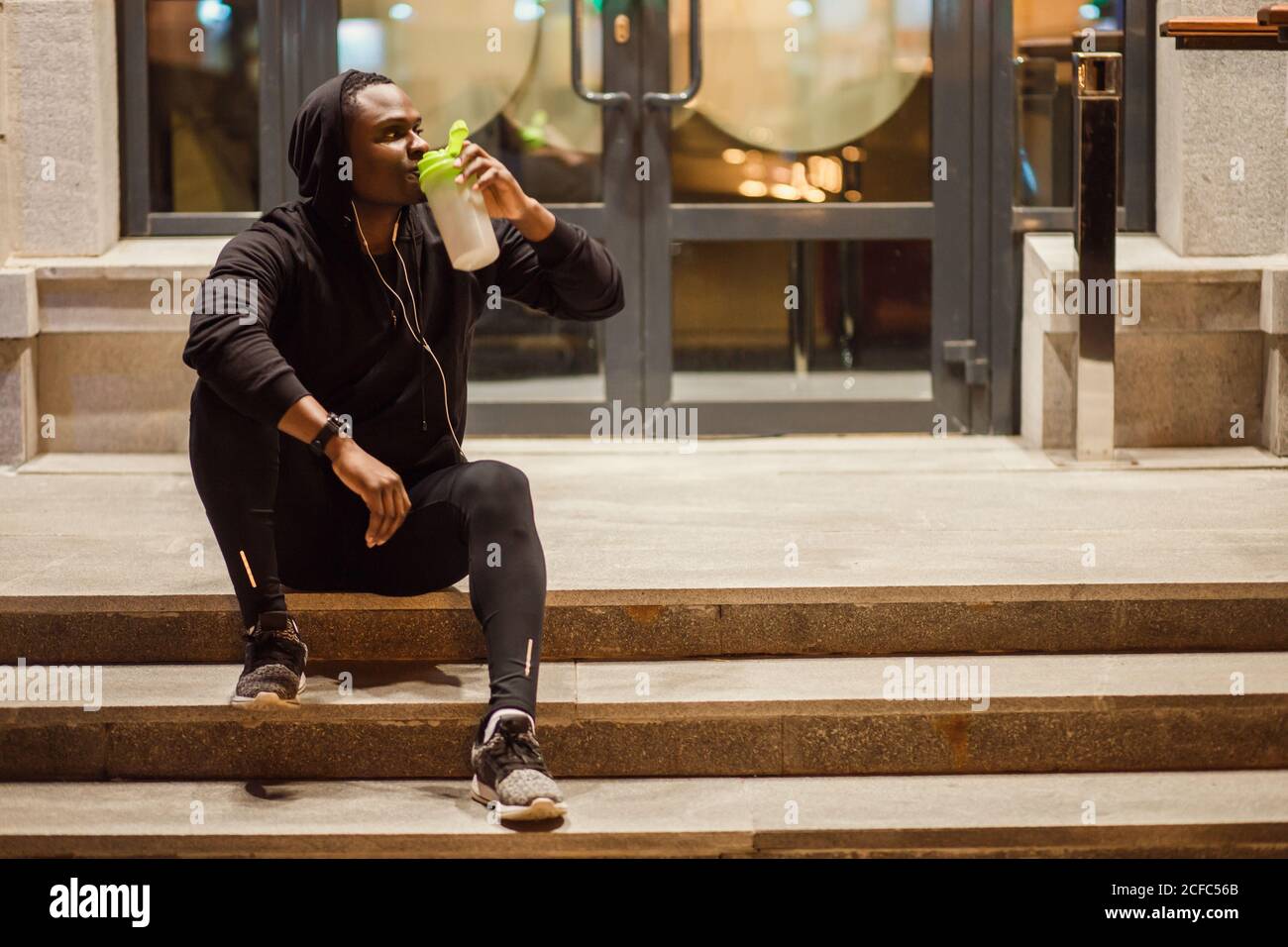 Young man drinking energy drink in the street with tracksuit resting and  hydrating Stock Photo - Alamy