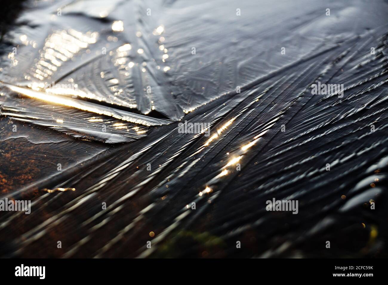 From above of ice surface of fiver in sunlight during winter in forest Stock Photo