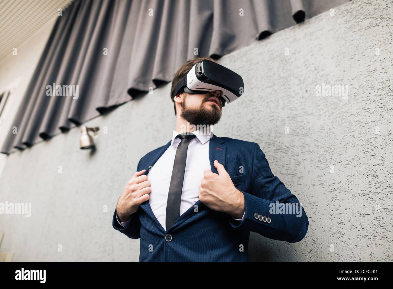 Bearded man wearing virtual reality goggles in modern coworking studio ...