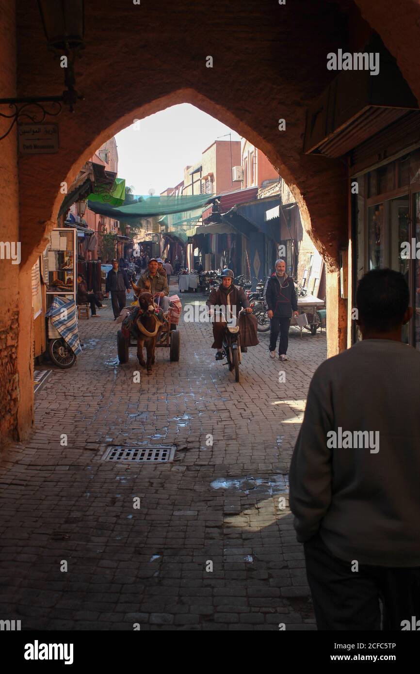 Side street in Marrakech souk with Berbers on scooters and companions Stock Photo