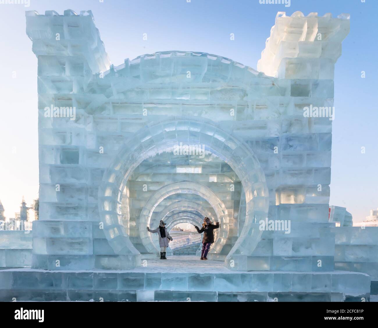 man and Woman in warm outwear standing on steps on illuminated castle during ice and snow sculpture festival in evening Stock Photo