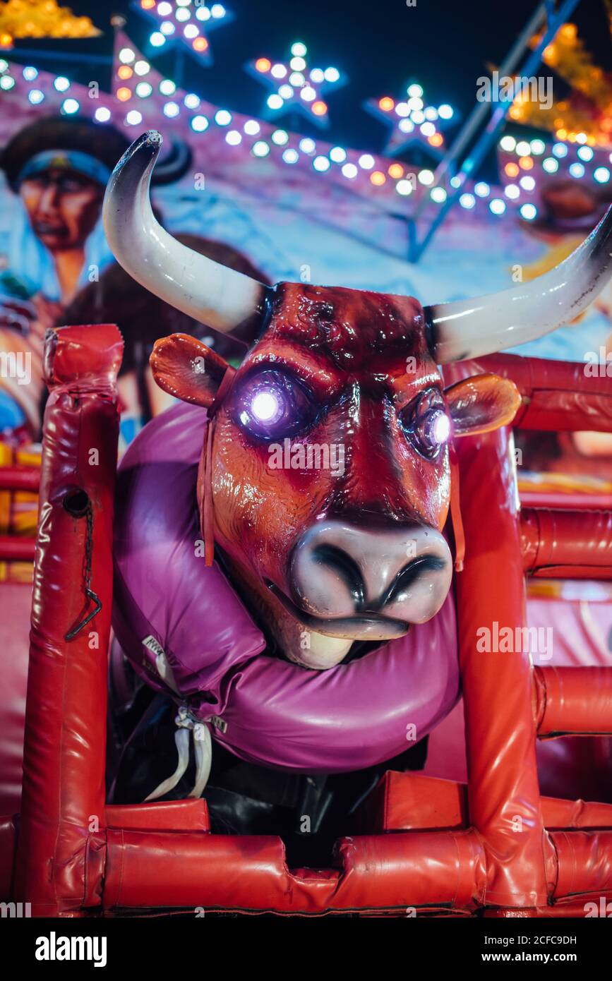 Low angle of modern mechanical bull with glowing eyes located on fairground in evening in city Stock Photo