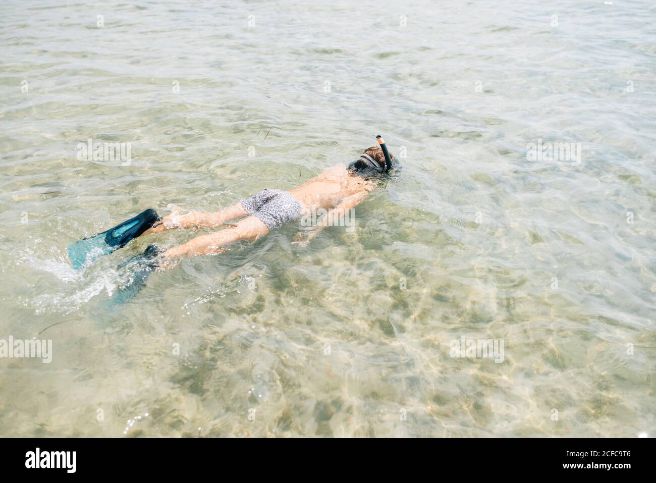 boy wearing flippers and diving mask while swimming and exploring