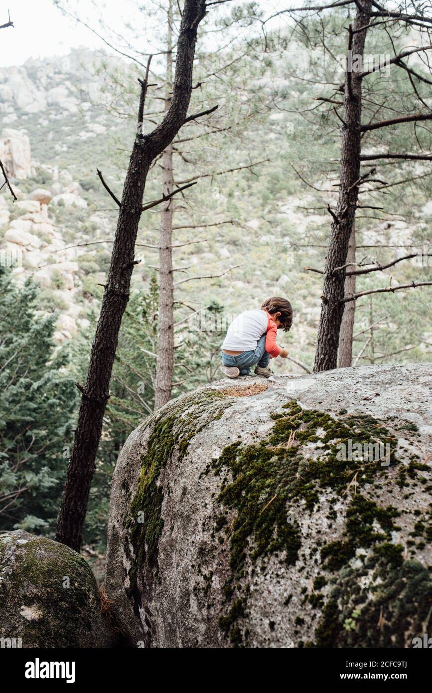 Little curious kid walking down rocky hillside exploring nature Stock Photo