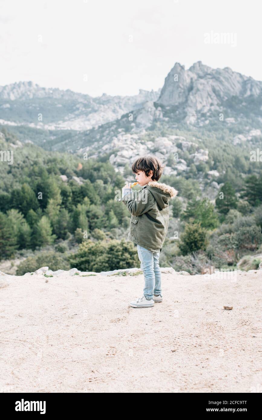 Little curious kid in coat walking down rocky hillside exploring nature Stock Photo
