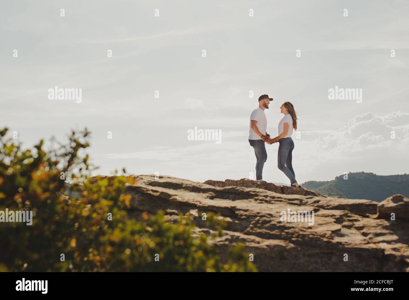 Loving couple holding hands while standing at mountain cliff Stock Photo