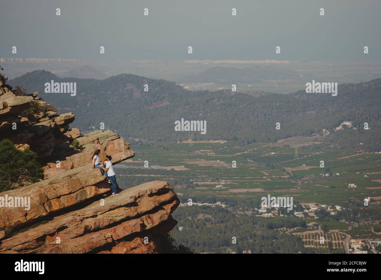 Distant loving couple standing on high cliff Stock Photo
