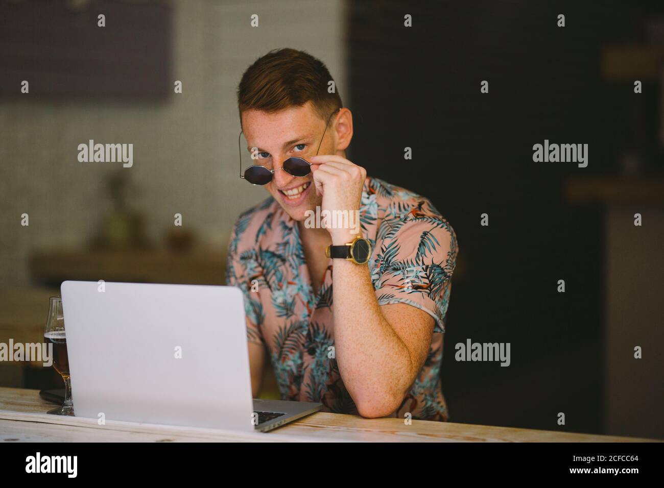 Focused young man working on laptop at table throughout a windows in coffee shop Stock Photo
