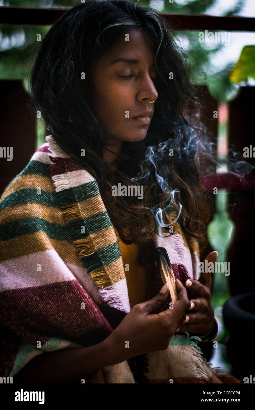 Spiritual young ethnic female with closed eyes in traditional clothes