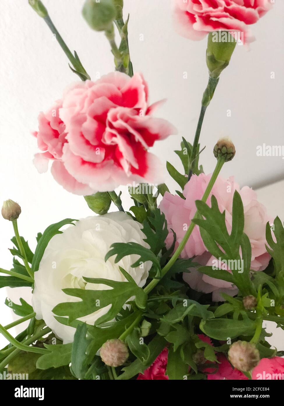 Spring bouquet with carnations and ranunculus, colorful bouquet in a white vase, Instagram style, Stock Photo