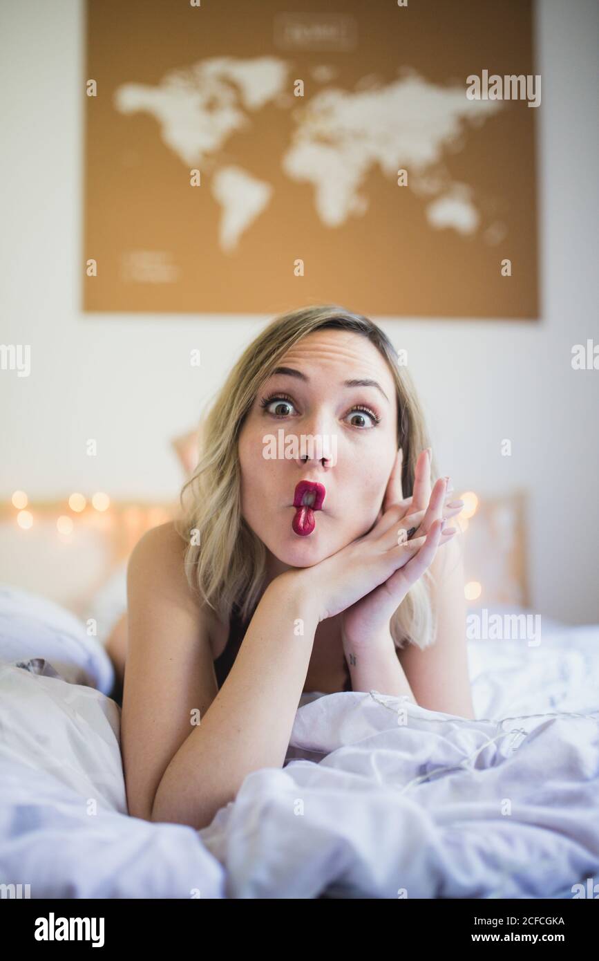 Young attractive Woman making funny faces while lying in bed in morning Stock Photo