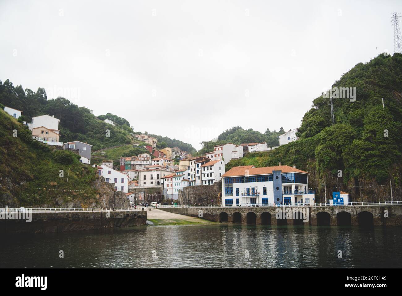 Calm small town with buildings on green hills and berth on quiet bay in Asturias Stock Photo