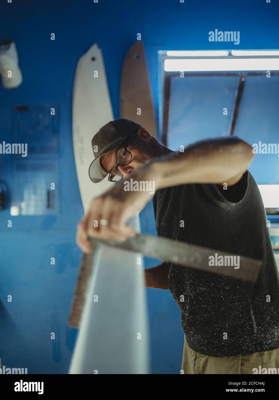 Carpenter diligently making surfboard in workshop Stock Photo