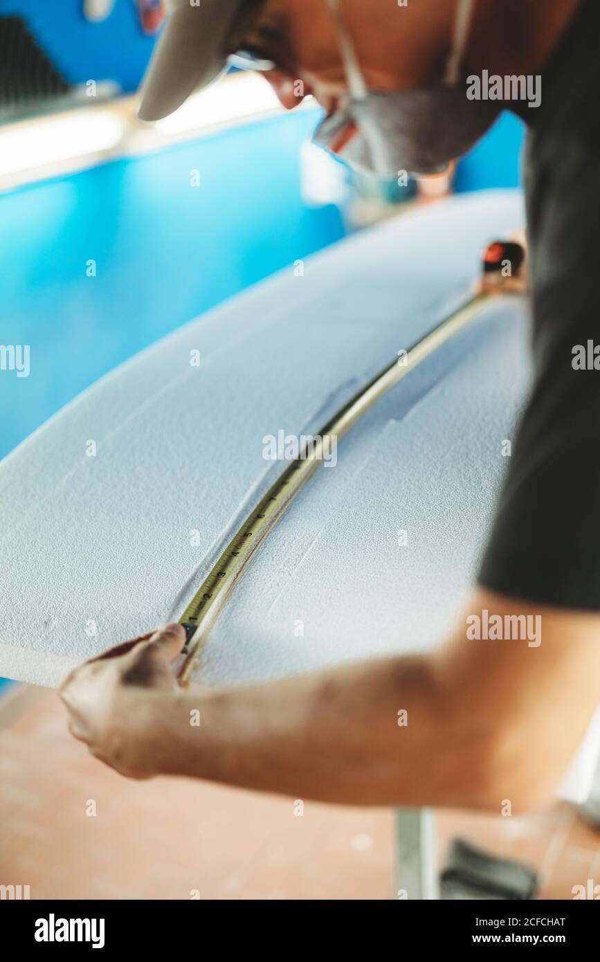 Workman with measuring tape making surf board Stock Photo