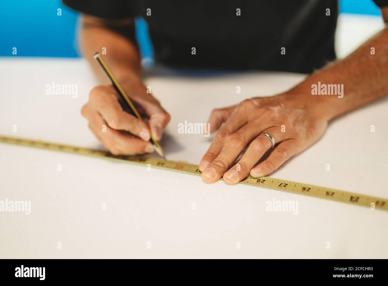 Workman with measuring tape making surf board Stock Photo