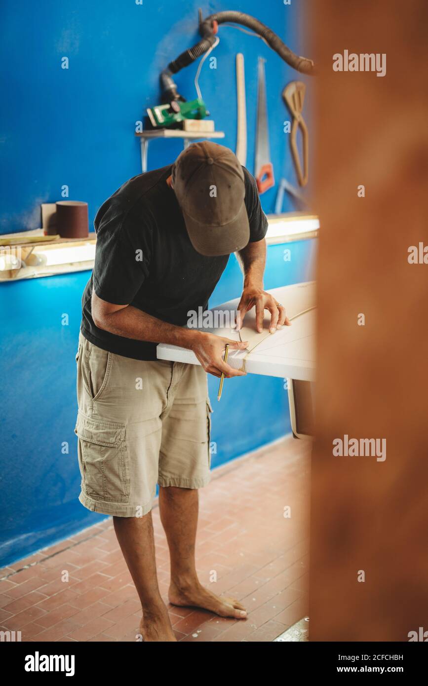 Workman with measuring tape making surf board Stock Photo