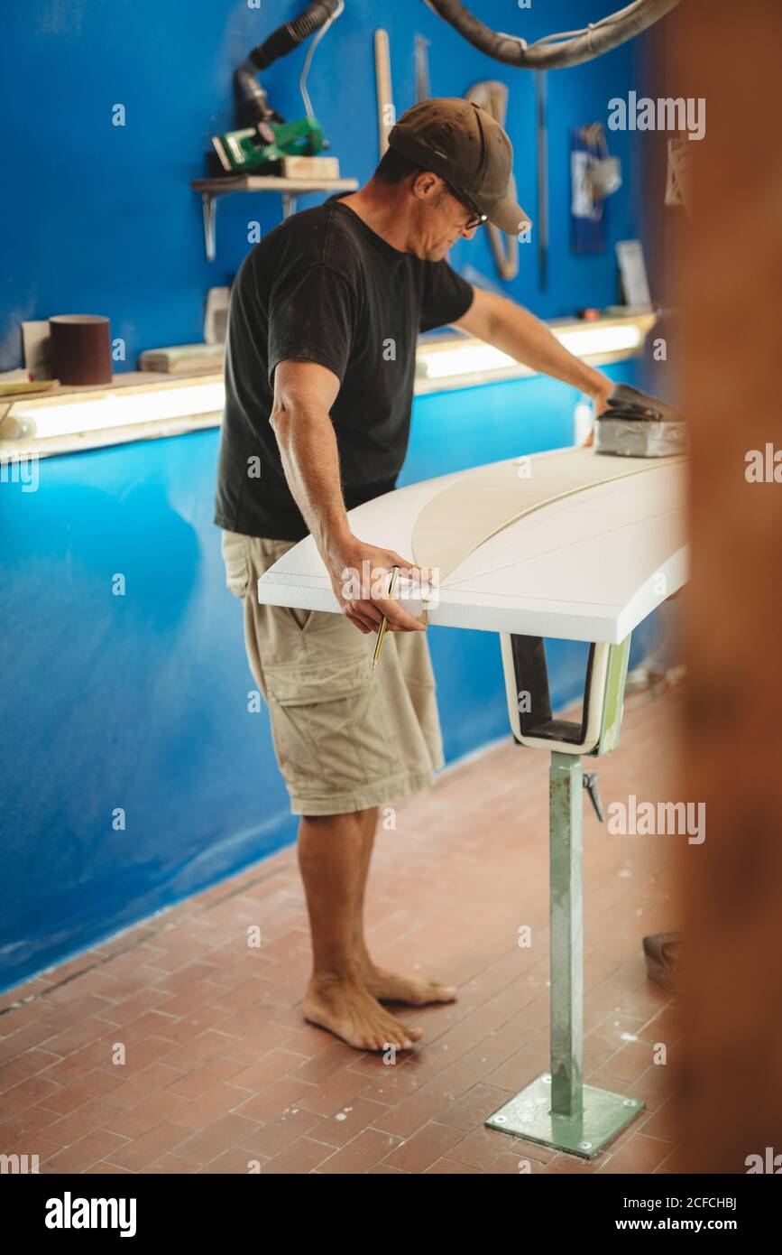 Workman with measuring tape making surf board Stock Photo