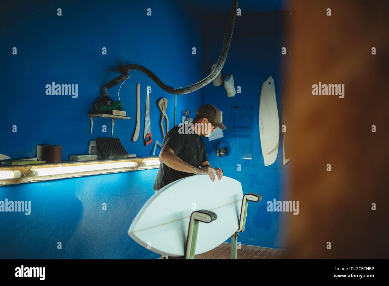 Carpenter diligently making surfboard in workshop Stock Photo