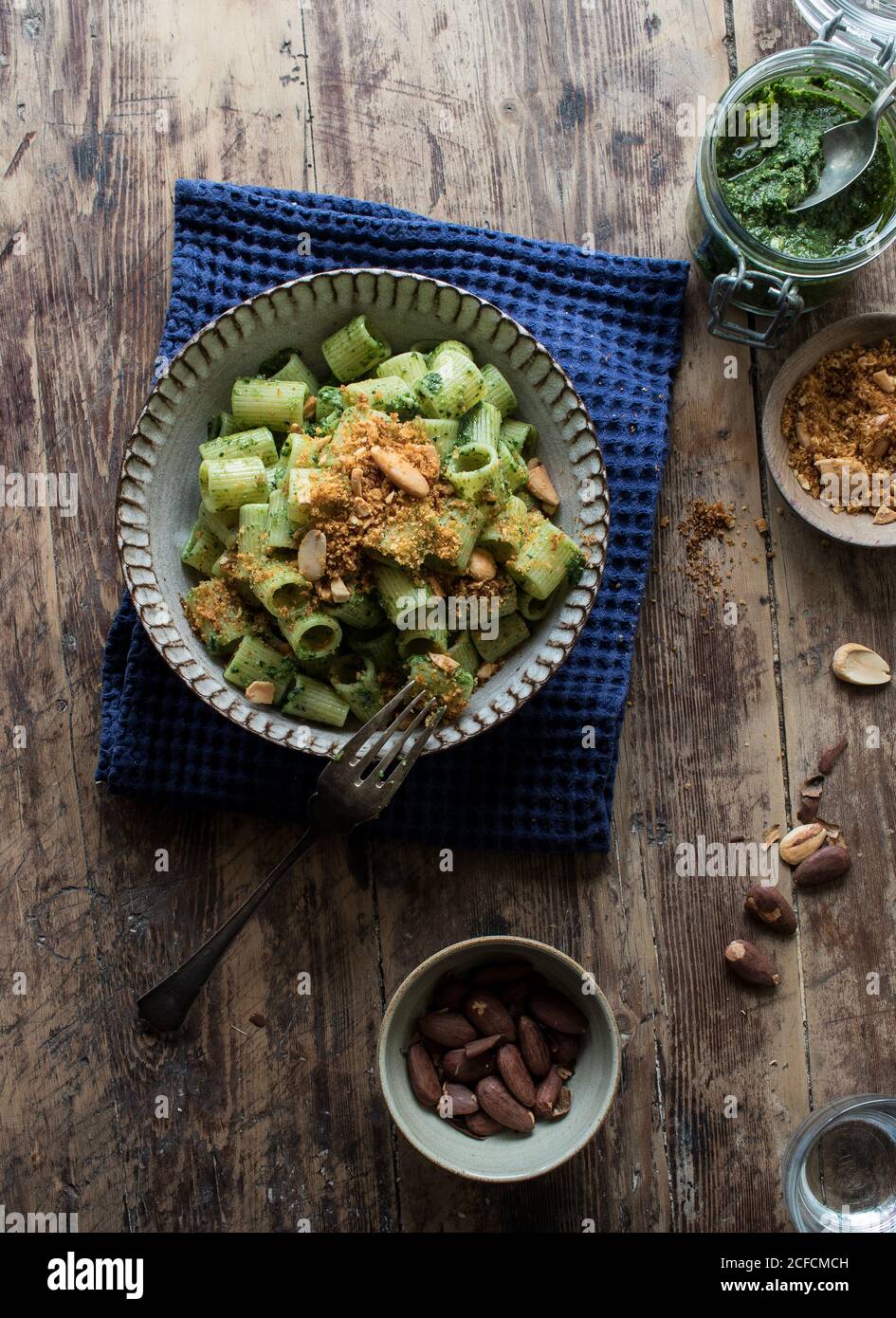 From above bowl of palatable pasta paccheri with fresh kale pesto and ground peanuts on timber tabletop Stock Photo