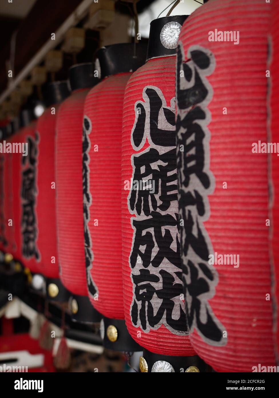 Row of authentic red lanterns with kanji hanging in traditional Shinto