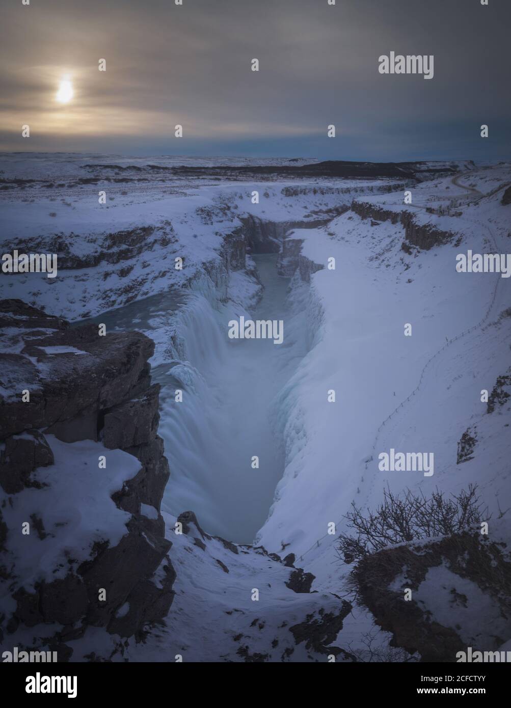 Cold Nordic scenery of snowy rocky terrain with big ravine under gray ...