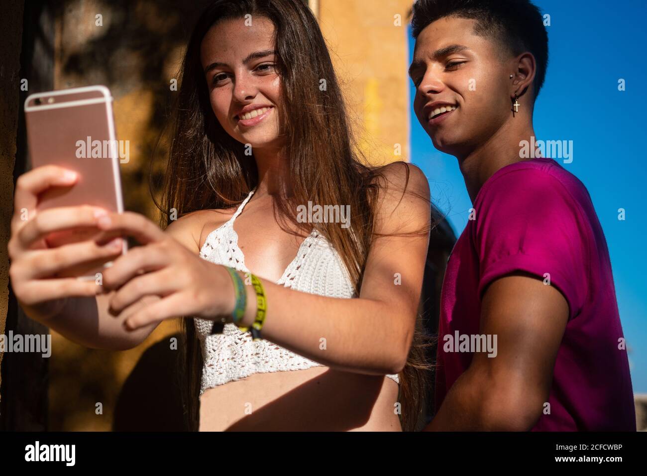 Charming young lady taking selfie on phone with content ethnic guy Stock Photo