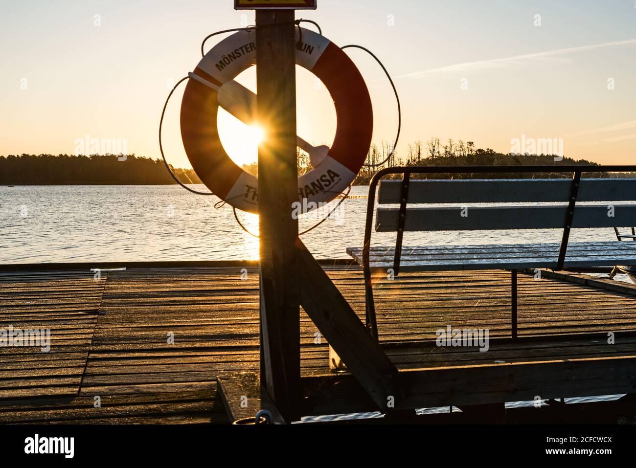 Evening sun shines through a lifebuoy hanging on a jetty Stock Photo