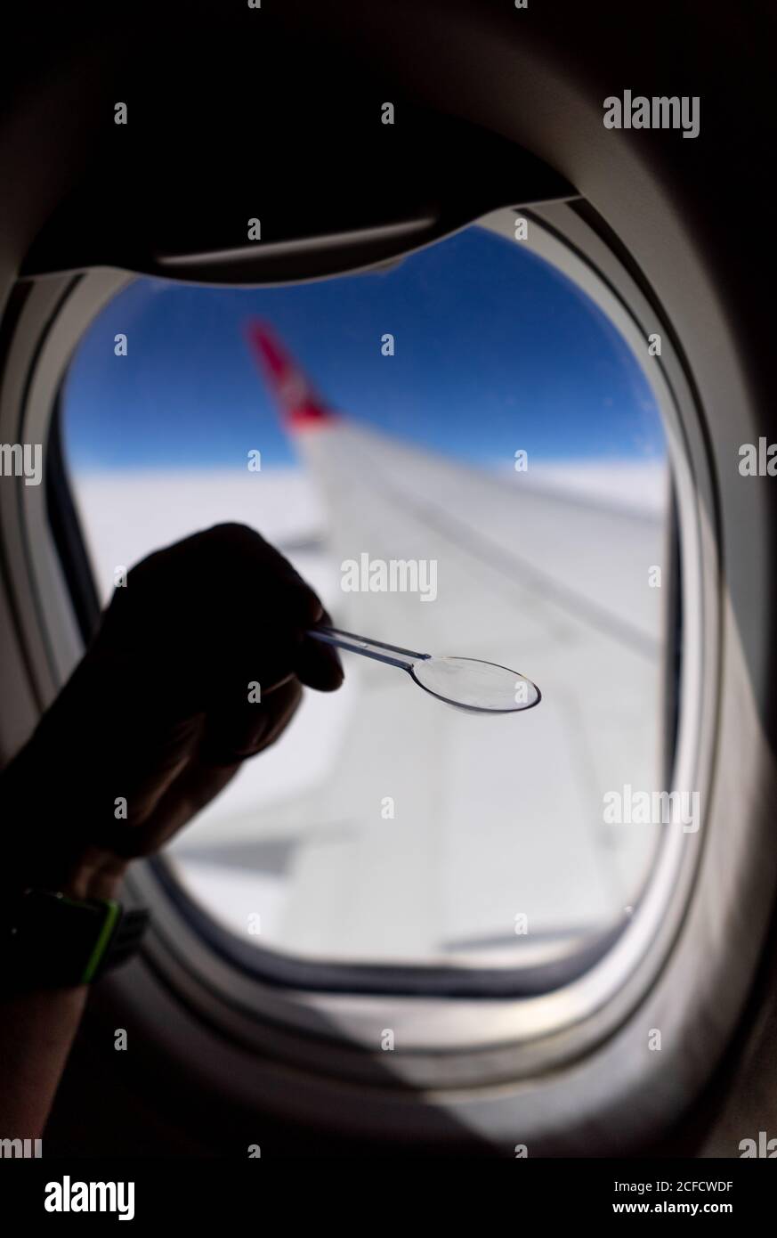 Crop passenger with teaspoon during flight in plane Stock Photo