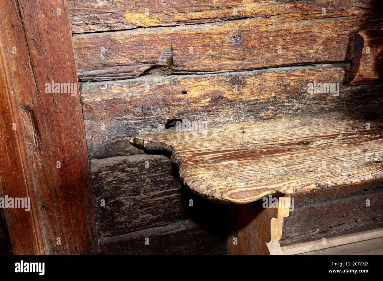 Bench in front of old wooden beams in the hallway of a mountain farmhouse from the 16th century Stock Photo