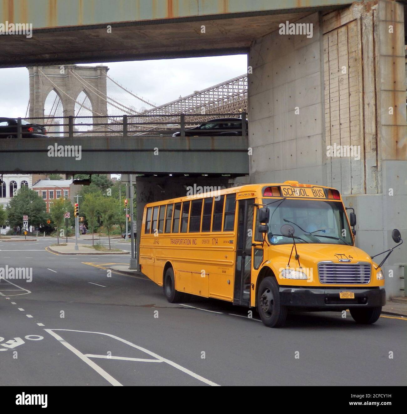 A parked American school bus with the Brooklyn Bridge in the background, New York City, United States Stock Photo