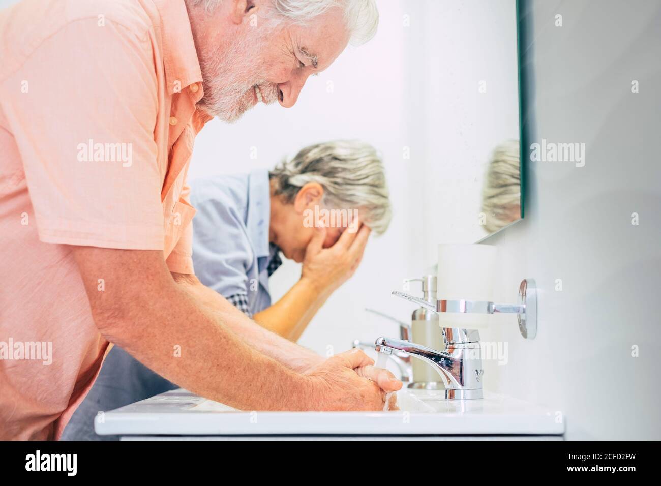 Hygiene and disinfect corona virus at home washing and cleaning hands together - old people use water in the bathroom for health lifestyle during Stock Photo