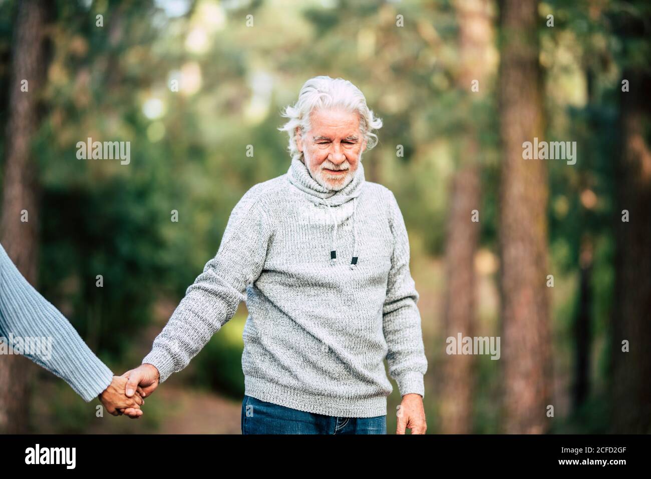 Assistance and disease alzheimer problems for old people- senior man holding hands and walk in the forest to enjoy the outdoor nature leisure activity Stock Photo