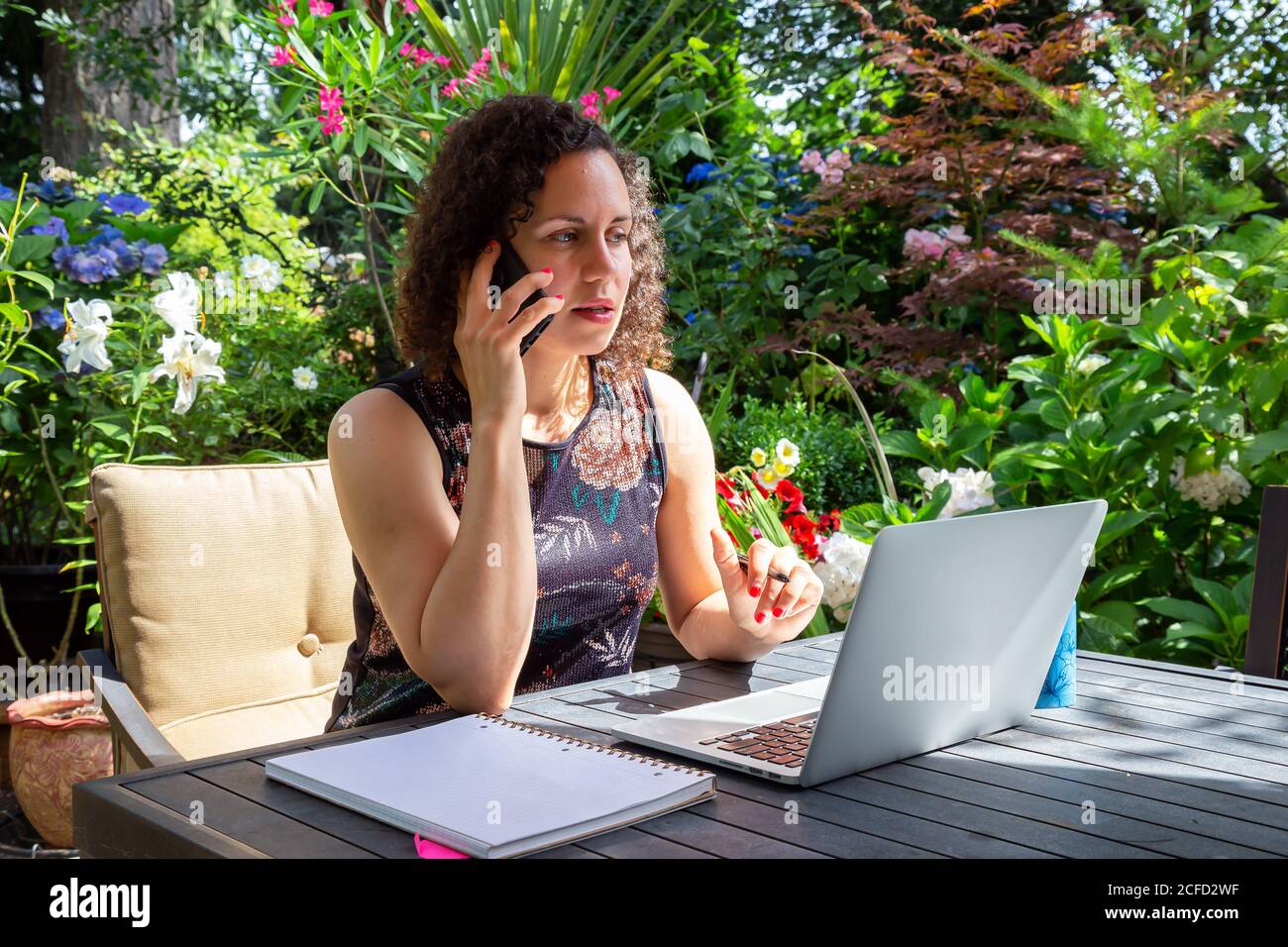 Young Caucasian Woman Working on a Laptop from Home in a Garden. Stock Photo