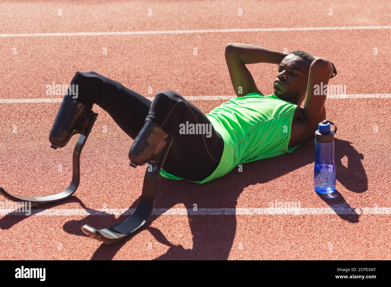 Male athlete with prosthetic legs laying on race track Stock Photo - Alamy