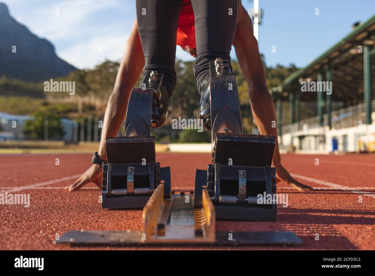 Rear view of male athlete with prosthetic leg bending on starting