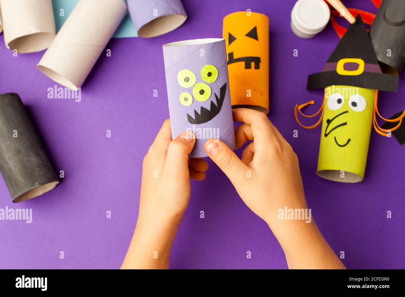 Boy makes Halloween toys from paper. toilet roll tube by hands. Creative  DIY for kids on traditional purple backgrpund. Home decor project party.  Hall Stock Photo - Alamy