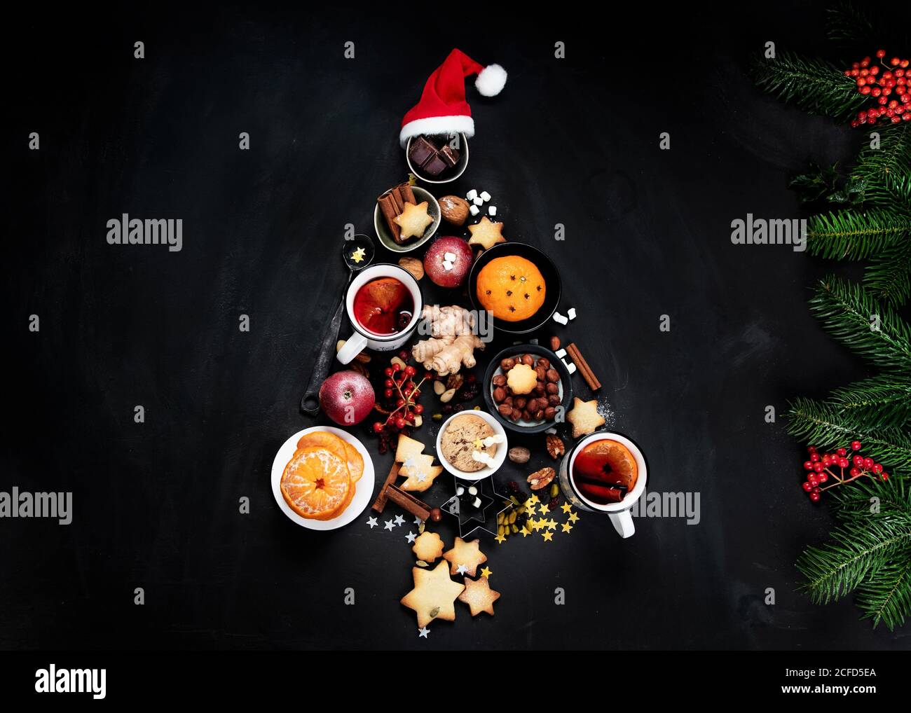 Christmas Tree made of holiday food on black background. Top view, flat lay  with copy space. Christmas concept. New Year Holidays background. Stock Photo