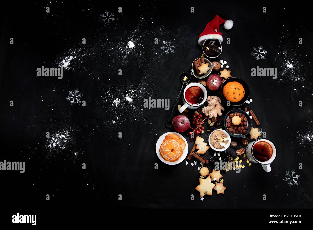 Christmas Tree made of holiday food on black background. Top view, flat lay  with copy space. Christmas concept. New Year Holidays background. Stock Photo
