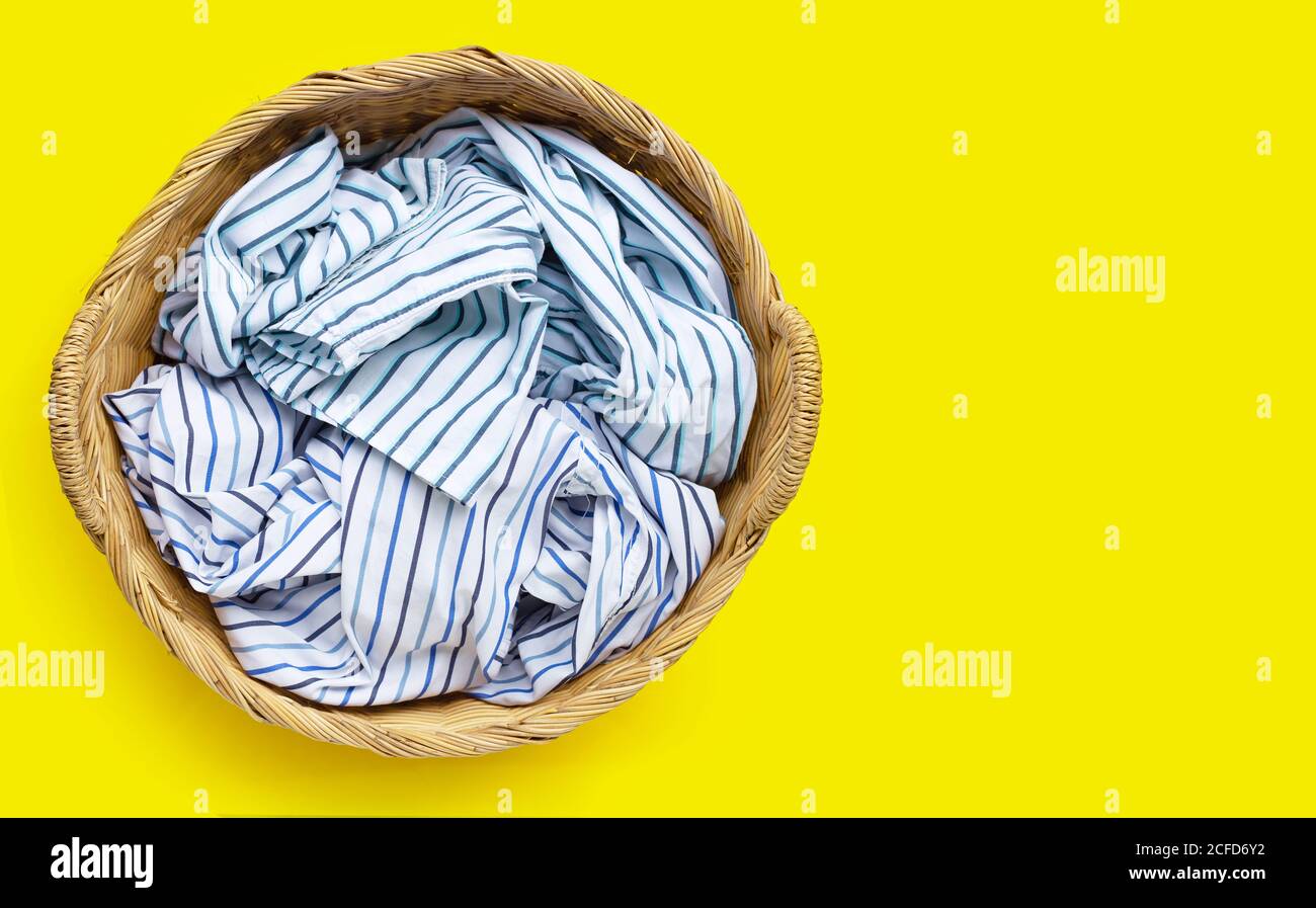 Clothes in laundry basket on yellow background. Copy space Stock Photo