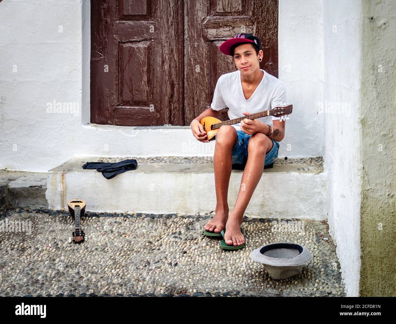 Lindos / Greece - August 19, 2014: A young street musician and his instrument in the streets of the old town. Stock Photo