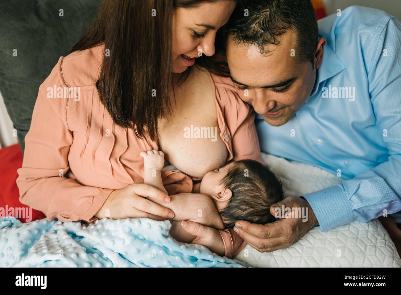 https://c8.alamy.com/comp/2CFD92W/from-above-faceless-mother-and-father-holding-on-hands-and-breastfeeding-newborn-baby-wrapped-in-blanket-on-bed-at-home-2CFD92W.jpg