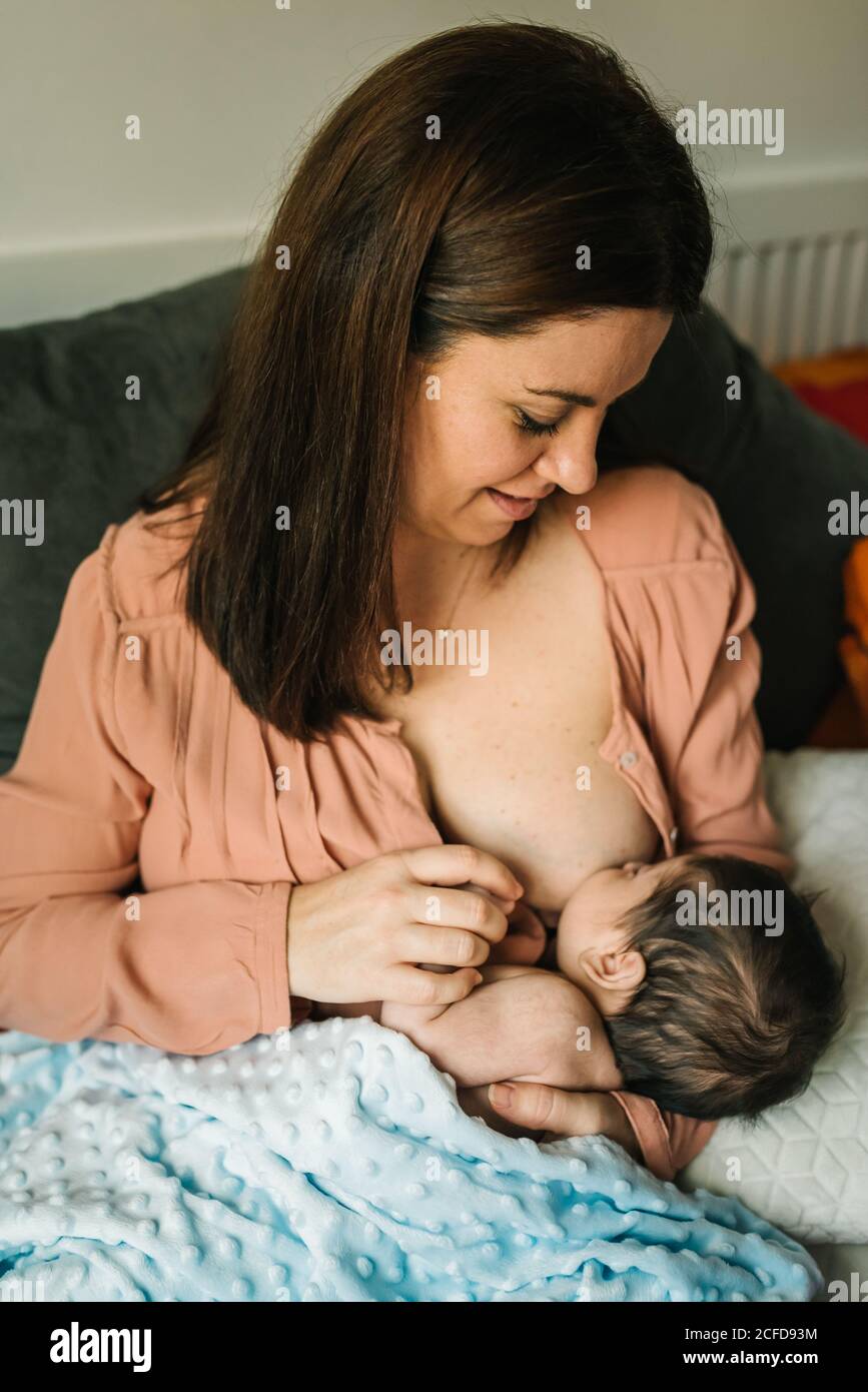 https://c8.alamy.com/comp/2CFD93M/from-above-young-mother-holding-on-hands-and-breastfeeding-newborn-baby-wrapped-in-blanket-on-bed-at-home-2CFD93M.jpg