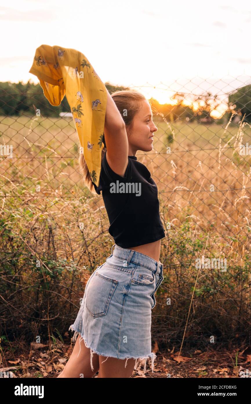 Side view of content bronzed Woman in casual wear taking off shirt near ...