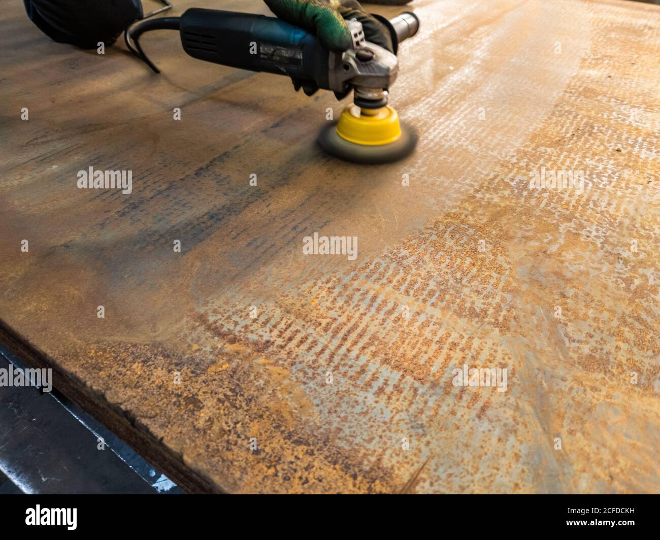 a process of manual cleaning of rusted sheet metal with steel brush on