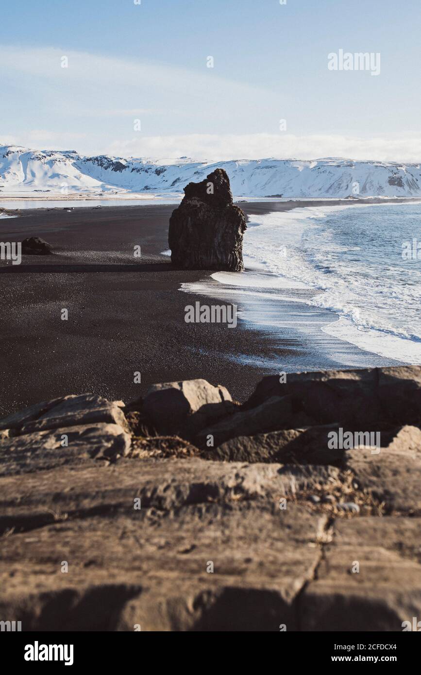 black lava beach of Reynisfjara with stand-alone rock at Cape of Dyrhólaey in winter Stock Photo